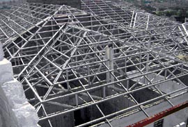 Roofer working on a new dormer by hammering nails into the roof edge